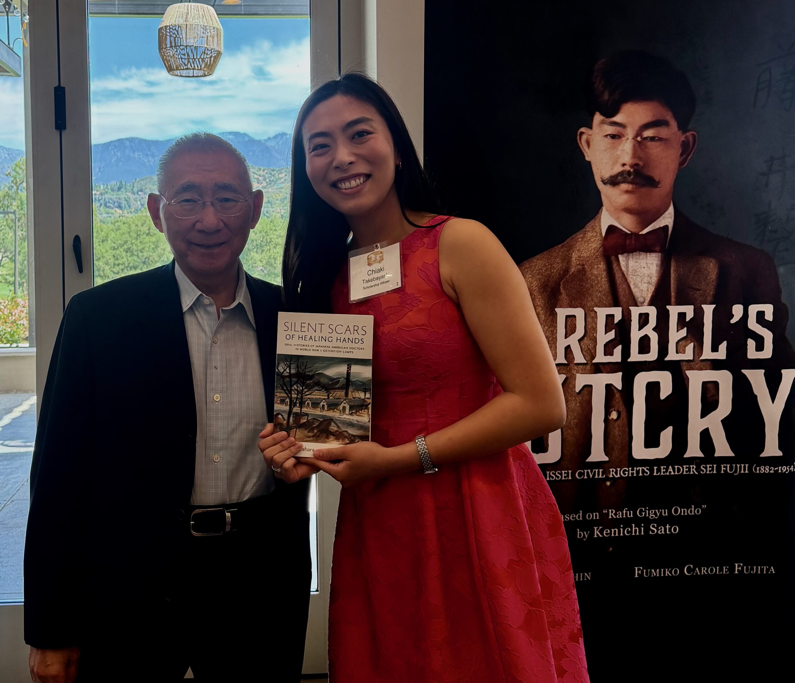Dr. Gordon Sasaki with scholarship winner Chiaki Takebayashi holding the "Silent Scars of Healing Hands" 
